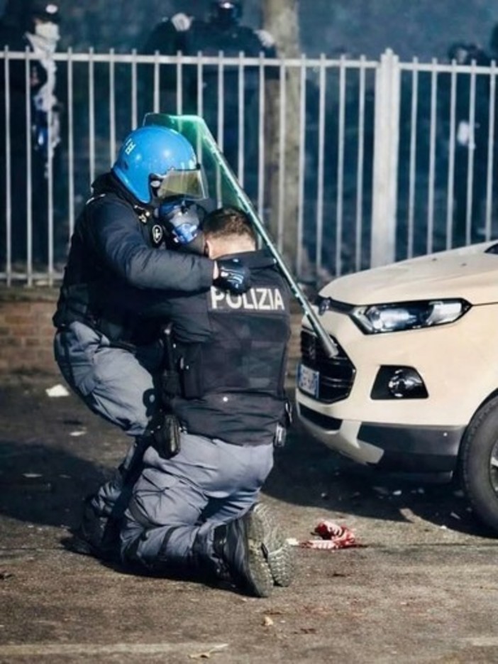 L'agente soccorso da un collega dopo essere stato accerchiato e picchiato - Foto dal profilo social di Alberto Cirio